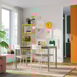 Área de jantar moderna com mesa amarela, arte de parede colorida e janela grande.