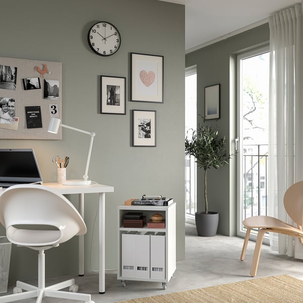 Escritório em casa moderno com mesa branca VIHALS, cadeira e unidade de armazenamento, com laptop, plantas e arte de parede.
