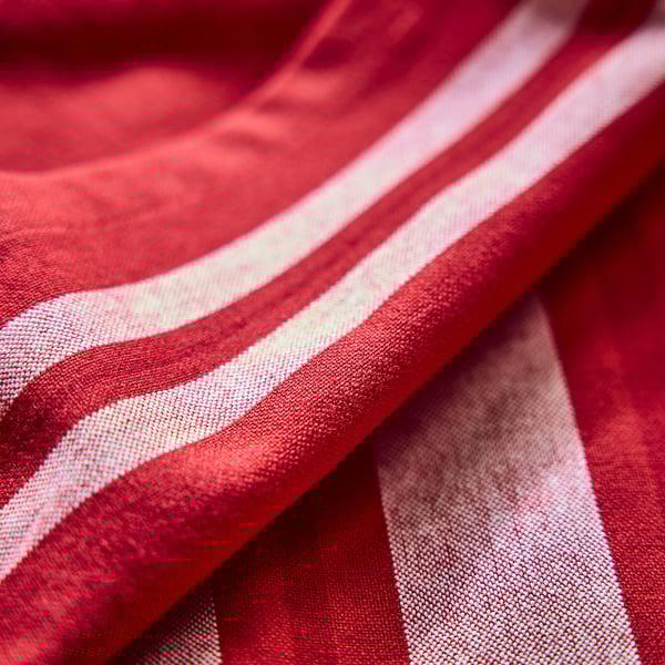 Close-up de tecido listrado vermelho e branco, mostrando textura lisa e tecida.