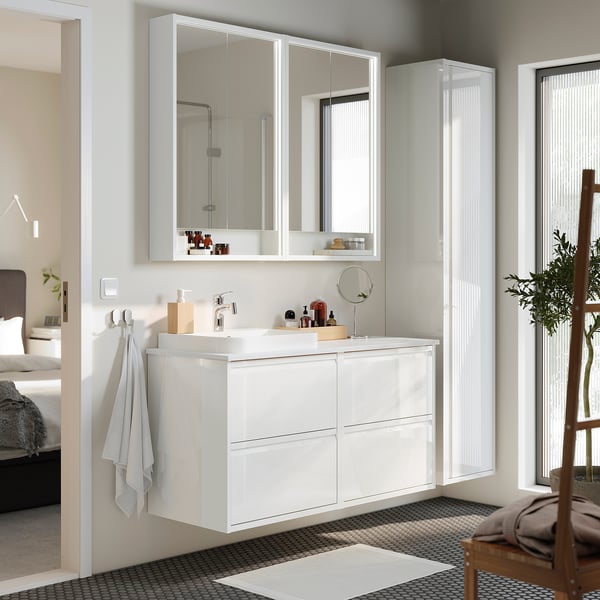 Modern white bathroom vanity with glossy finish and multiple drawers, paired mirror.