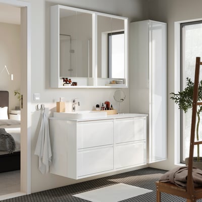 Modern white bathroom vanity with glossy finish and multiple drawers, paired mirror.