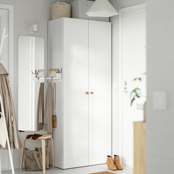 LASTARE wardrobe between mirror and wall. Narrow, vertical storage with doors, baskets, and lamp.