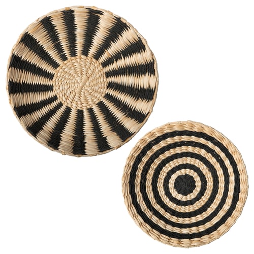 Two handwoven round wall hangings, one with black zigzags, the other with black spirals, made from banana fibres and cotton.