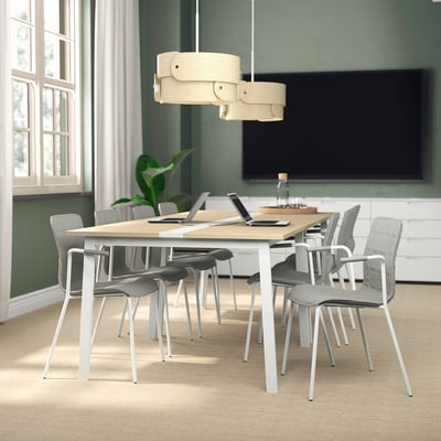 Modern MITTZON conference table with grey chairs, large screen, and unique pendant light. Light wood top, white legs, and green walls.