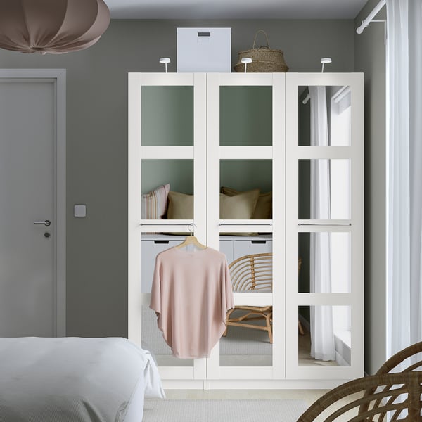 Modern bedroom with PAX wardrobe, mirror doors, and bed. Grey door, white bed, beige rug.