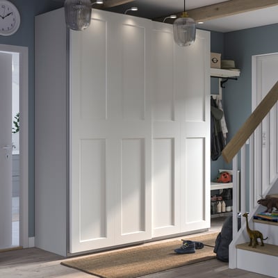 Modern entryway with white PAX wardrobe, beige rug, blue wall, and wooden ceiling. Two gold pendant lights, staircases with toys.