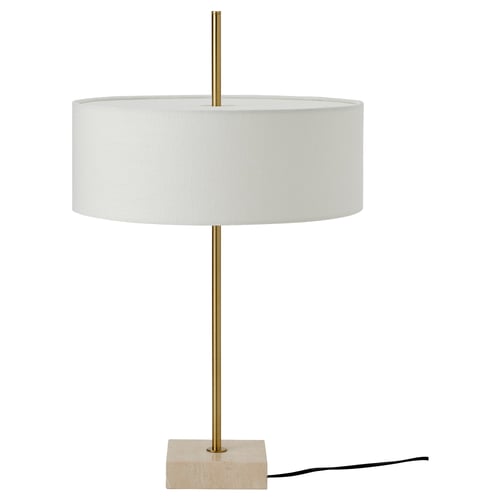 The STOCKHOLM 2025 lamp, showcasing a brass-colored foot, travertine base, and textured textile shade, exuding an elegant design.