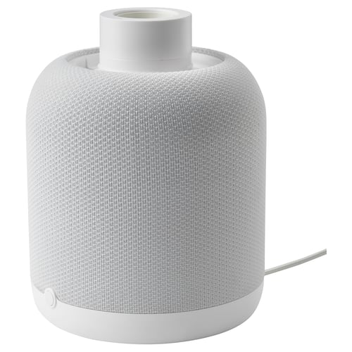A white ikea SYMFONISK wifi speaker lamp base. Its cylindrical, wrapped in a fabric cover, and designed for use with a lamp shade.