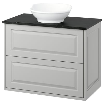 Modern white bathroom vanity with black countertop and bowl-shaped sink.