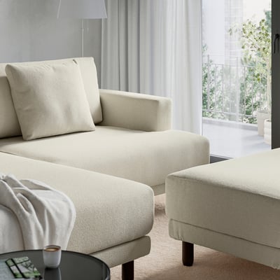 Modern cream-colored sectional sofa with thick cushions and a cosy, inviting look, near a window with greenery visible.