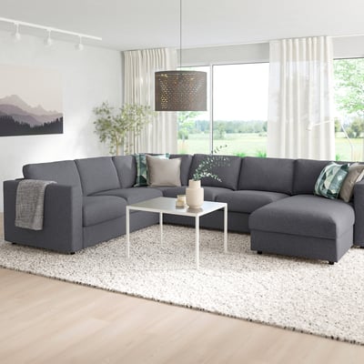 Modern grey VIMLE sectional sofa with chaise, white coffee table, white rug, large window, pendant lamp, wall artwork, and plants.