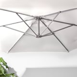 O umbrelă de soare albă de înaltă calitate, cu un cadru metalic robust, cu sistem de aerisire și manivelă pentru deschidere și închidere ușoară.