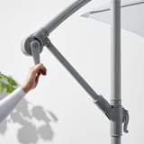 Persoană care reglează manivela umbrelelor de soare BAGGÖN, controlându-i unghiul.