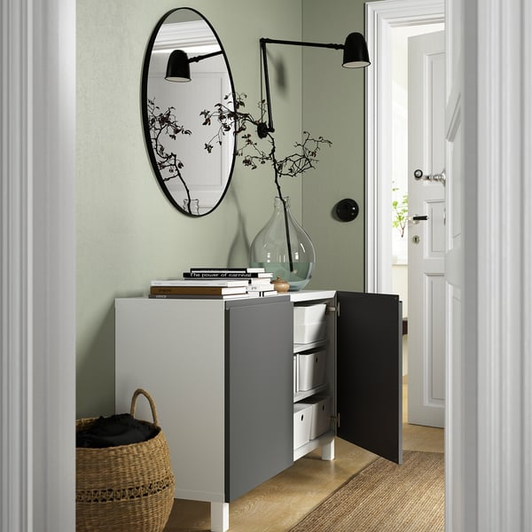 Bufet modern montat pe perete cu uși deschise, rafturi reglabile și depozitare ascunsă lângă o intrare cu obiecte decorative și iluminat.