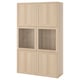 Un dulap de depozitare ikea BESTÅ maro deschis. Are patru secțiuni: două cu uși de sticlă și două uși solide, afișând un design modern și minimalist.