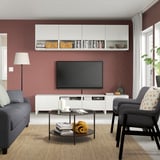 Living modern cu perete roșu, suport TV BESTÅ, canapea, măsuță de cafea și lampă.