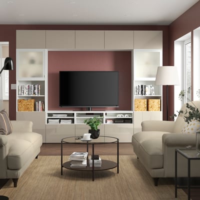 Living modern cu unitate TV BESTÅ, televizor, rafturi, canapele bej și măsuță de cafea.