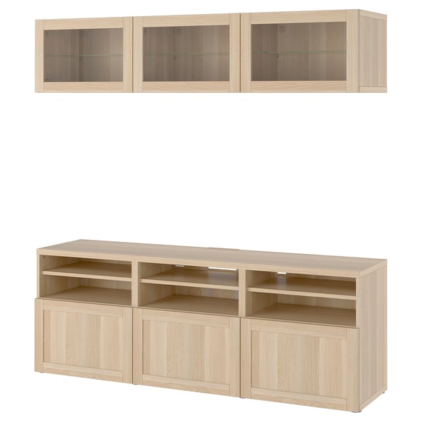 Combinație de depozitare pentru televizoare Ikea BESTÅ cu finisaj stejar deschis, cu rafturi reglabile, gestionare a cablurilor, dulapuri montate pe perete și uși din sticlă.