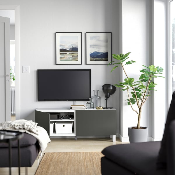 Living modern: pereți gri, suport TV, plantă, canapea, lampă.