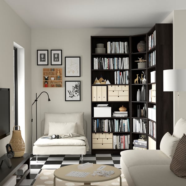 Living modern cu bibliotecă BILLY maro închis, fotoliu alb, canapea, lampă de podea și covor de șah.