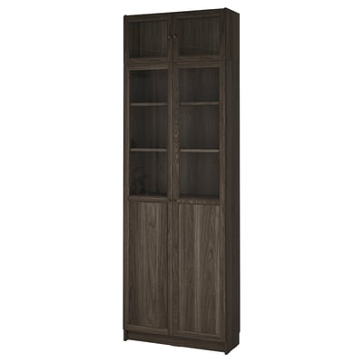 O bibliotecă BILLY înaltă, maro închis, cu uși de sticlă. Are mai multe rafturi pentru depozitare.