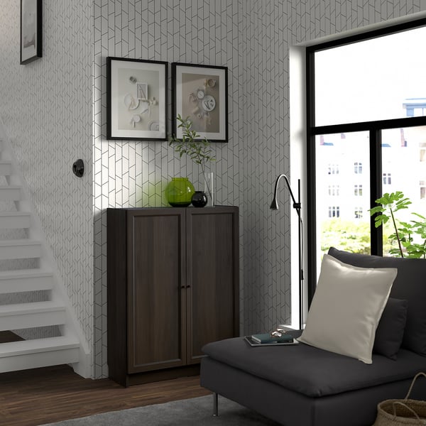 Living modern cu bibliotecă BILLY, canapea gri, fereastră mare și scară. Decorul include rame și plante.