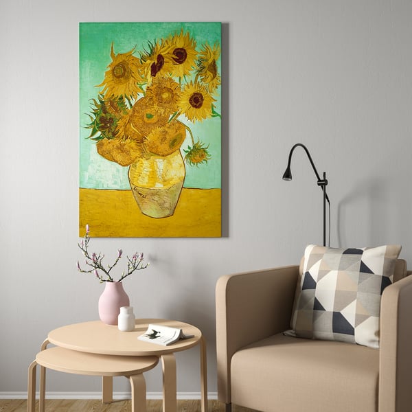 Vincent van goghs floarea-soarelui imprimat pe pânză în galben și verde într-o cameră minimalistă, flancată de fotoliu și lampă de perete.