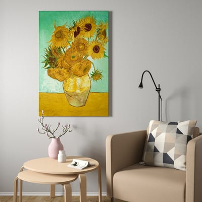 Vincent van goghs floarea-soarelui imprimat pe pânză în galben și verde într-o cameră minimalistă, flancată de fotoliu și lampă de perete.