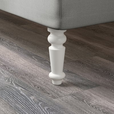 Prim-plan al piciorului din lemn vopsit în alb pe podea din lemn închis la culoare. Finisaj neted, de calitate.