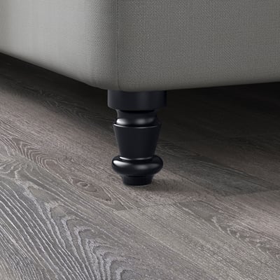 Mobilier tapițat gri închis cu picioare din lemn masiv negru pe podea din lemn texturat.