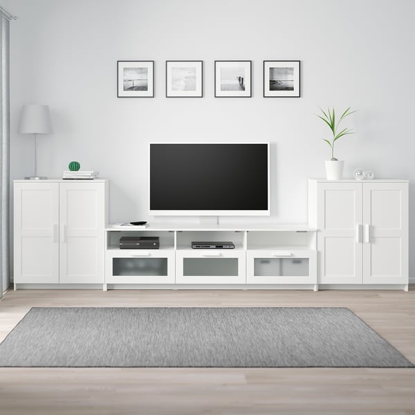 Living modern cu suport TV alb BRIMNES, televizor montat, opere de artă și decor.