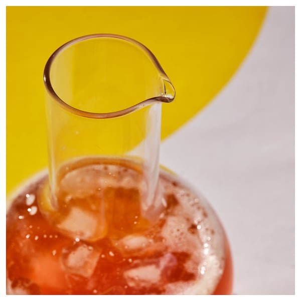 Carafă de sticlă care toarnă lichid într-un pahar, prezentând claritate și design elegant.