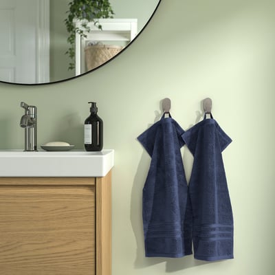 Prosoape BROKGLIM albastre pe cârlige lângă chiuvetă modernă cu chiuvetă, săpun și oglindă. Bumbac organic, absorbant, bordură decorativă.