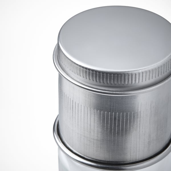 Prim-plan al capacului din oțel inoxidabil pe recipient cilindric, prezentând calitatea și designul.