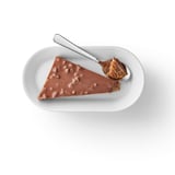 Caramel de migdale acoperit cu ciocolată pe farfurie cu lingură