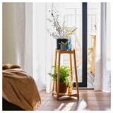 Suport pentru plante din lemn cu trei niveluri care țin vaze și plante, poziționate lângă o fereastră.