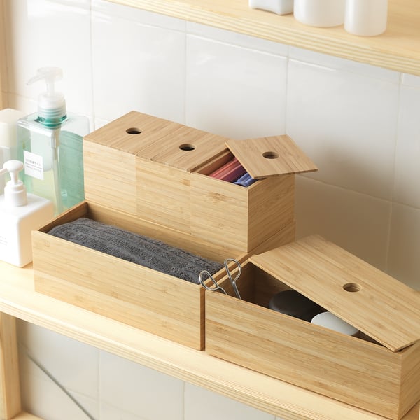 Cutii de bambus pe tejghea: una deschisă, foarfece înăuntru, bine organizată.