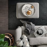 Living confortabil: canapea gri cu carouri, laptop, căști, pături, tavă de gustări pe covor, coș cu perie renovatoare, plantă.