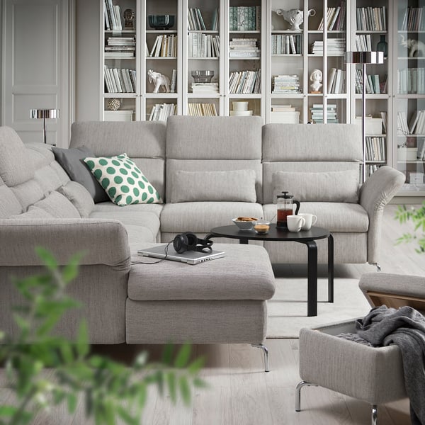 Living modern cu canapea gri FAMMARP, taburet, măsuță de cafea și raft plin de cărți și obiecte decorative.