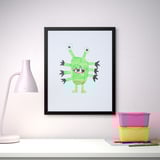 Artă monstru verde înrămată cu o lampă și cutii de depozitare pe un birou alb.