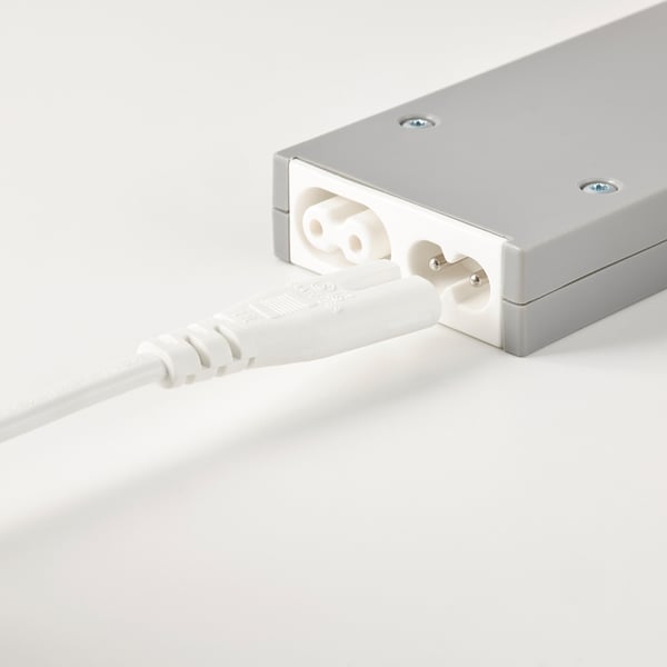 Un adaptor de alimentare argintiu conectat la o priză și un cablu alb, utilizat pentru conectarea lămpii de rețea cu control wireless.