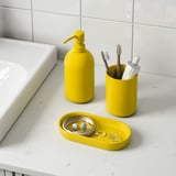 Set baie galben pe blat de marmură: dozator de săpun, suport periuță de dinți și tavă cu bijuterii.