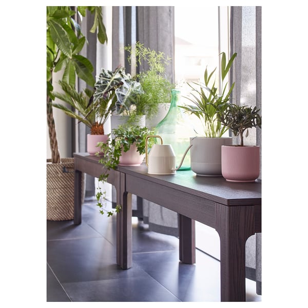 Configurație interioară modernă cu consolă gri, jardiniere roz și albe, plante, stropitoare.