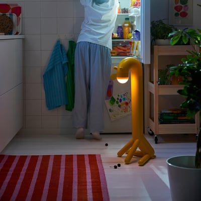 Copil la frigider, lampă de girafă în apropiere.