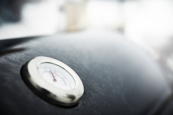 Prim-plan al termometrului încorporat pentru grătare GRILLSKÄR, argintiu, rotund, încorporat în hota emailată neagră.