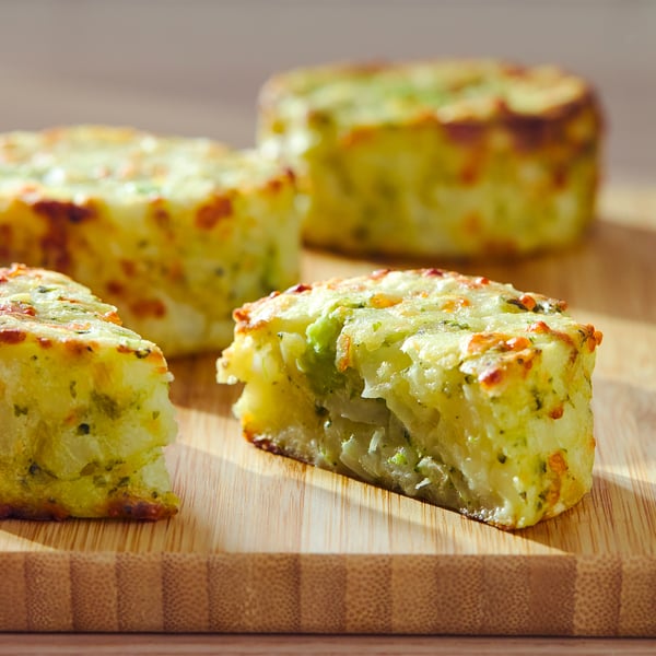 Patru caserole de brânză și legume pe scândură de lemn, blat maro-auriu, formă dreptunghiulară.