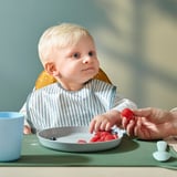 Bebeluș care mănâncă cu bavetă GULDVÄVARE, față cu dungi, spate punctat, curea reglabilă pentru gât.