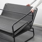 Persoana reglează spătarul canapelei extensibile HAMMARN, transformându-l din poziție de șezut în poziție de dormit.