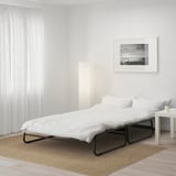 O canapea extensibilă modernă din metal negru cu lenjerie de pat albă, rapid transformabilă pentru dormit.