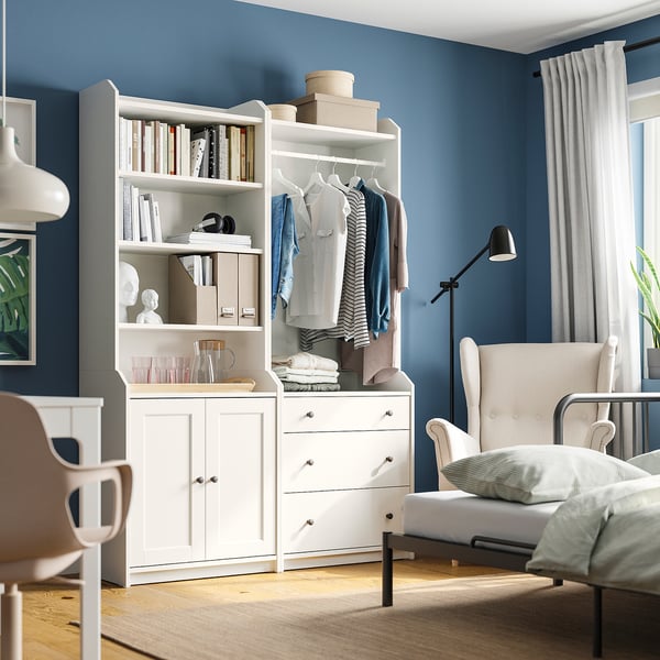 Dormitor modern cu unitate de depozitare albă HAUGA, pereți albaștri, mobilier alb, podea din lemn.